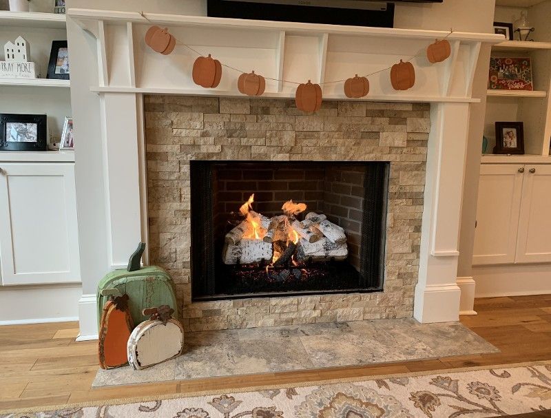 A fireplace in a living room with pumpkins on the mantle.