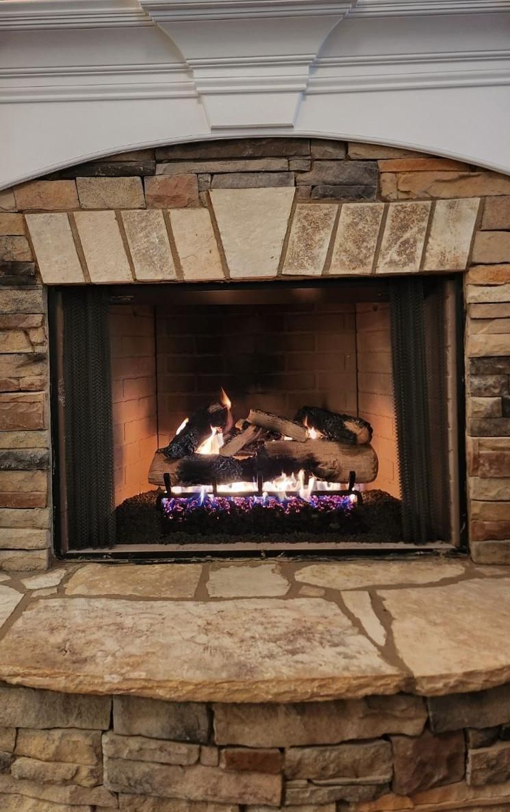 A fireplace with a brick wall and a stone mantle.