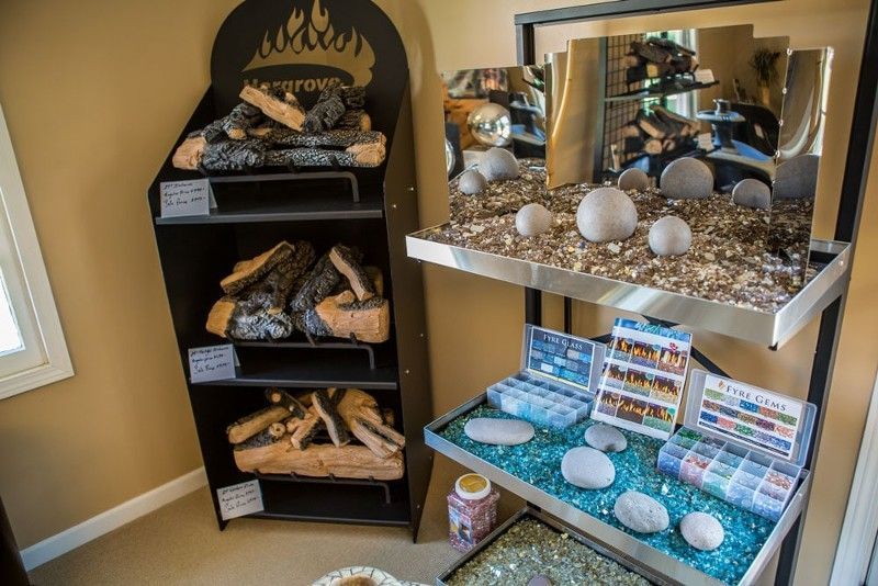 A room with a shelf filled with firewood and rocks.