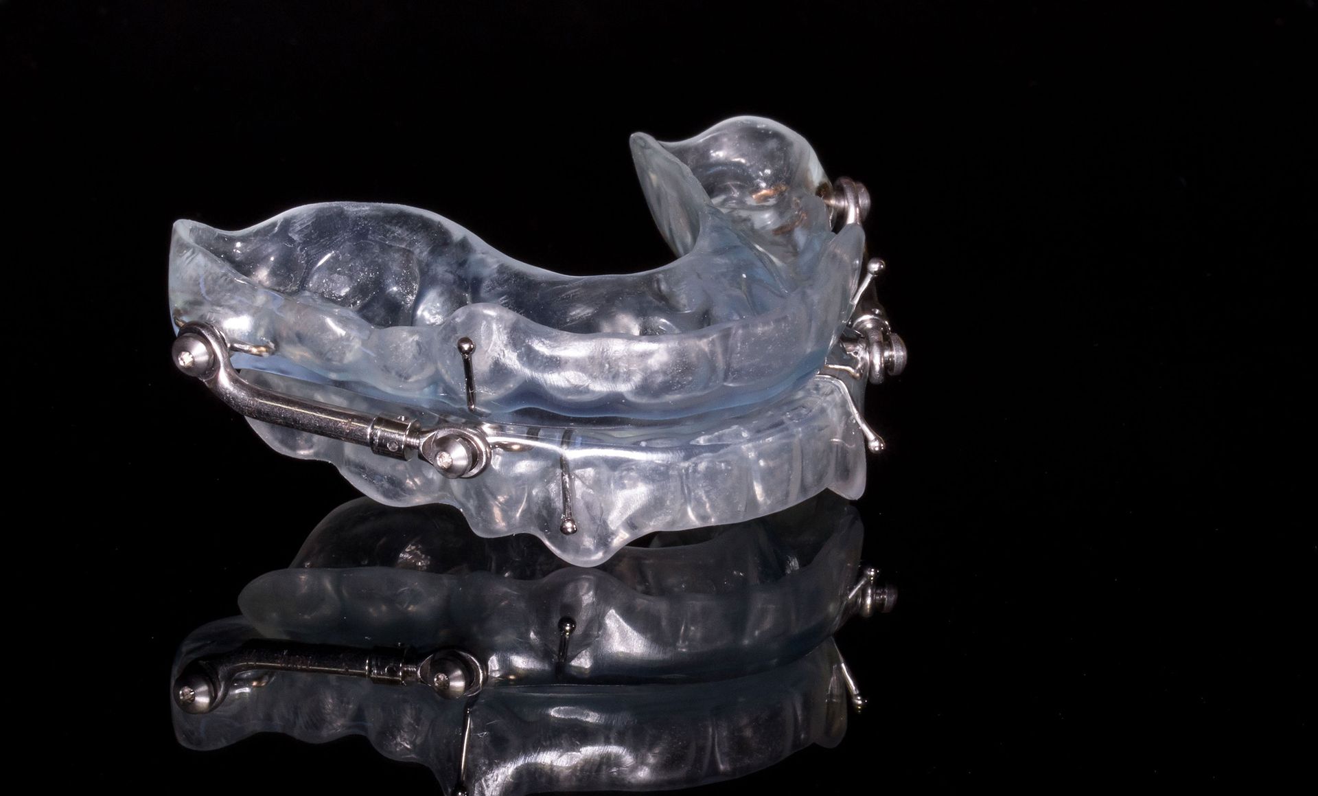 A clear mouth guard is sitting on a black surface.