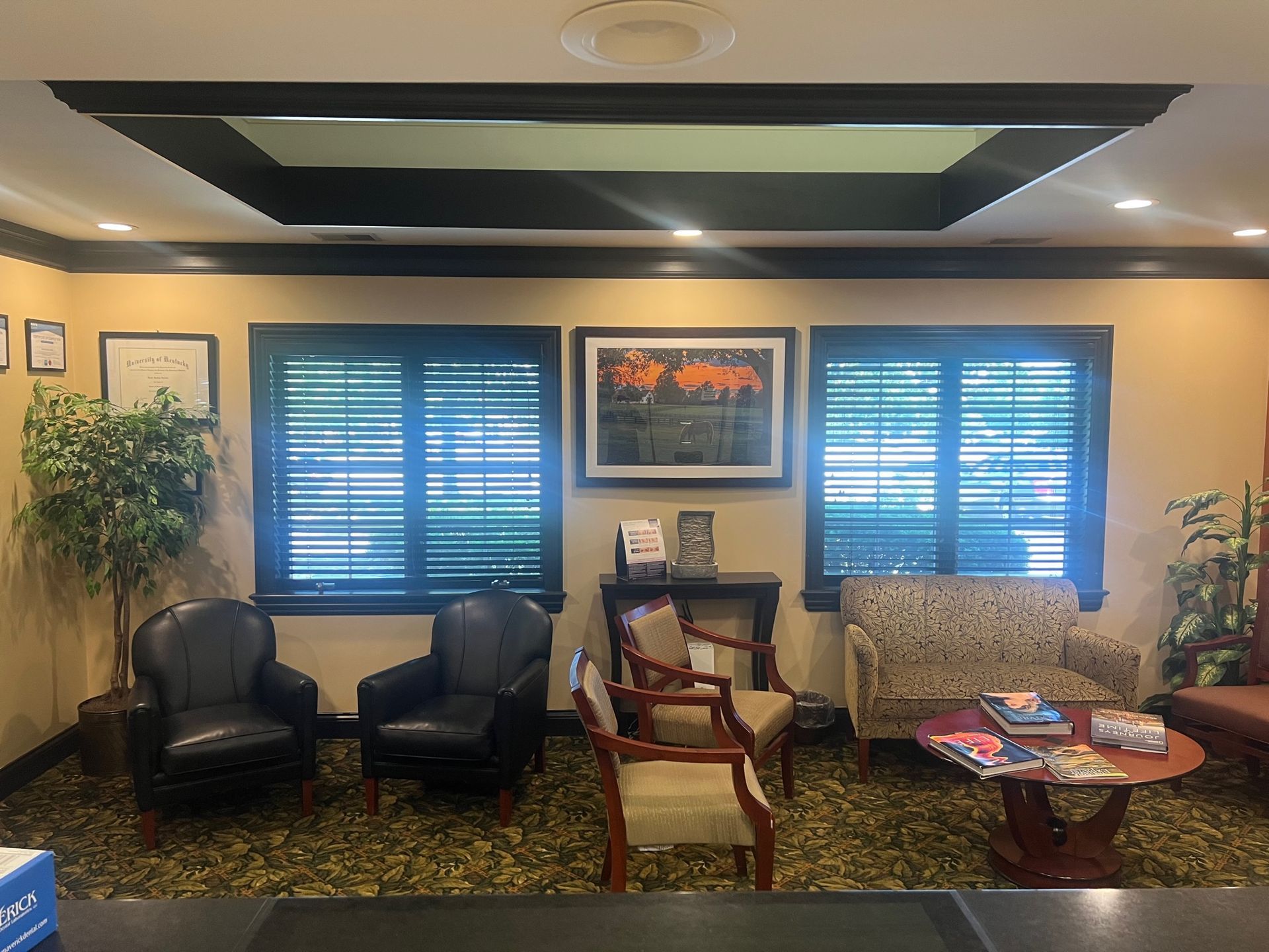 A waiting room with a couch, chairs, a table, and shutters.