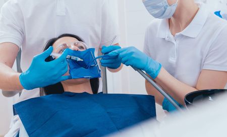 A woman is getting her teeth examined by a dentist in a dental office.