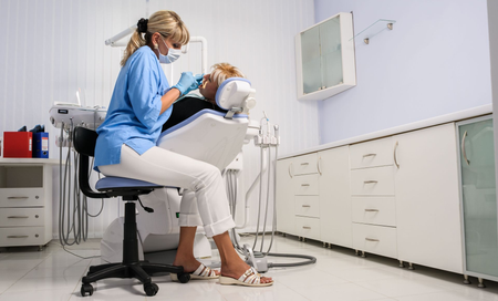 Dentist examining a patient in a bright dental clinic, with cabinets and equipment nearby