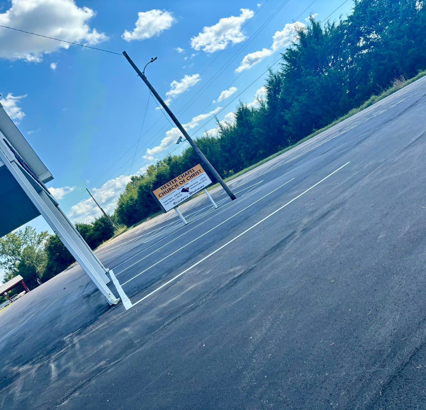 Empty parking lot with a sign, utility pole, and blue sky on a sunny day