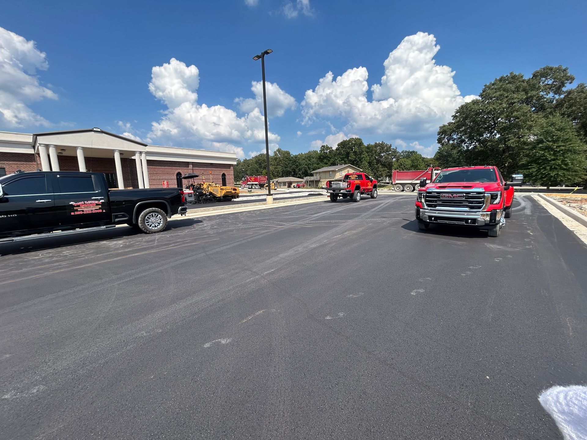 Parking lot with black and red trucks under a bright blue sky with clouds