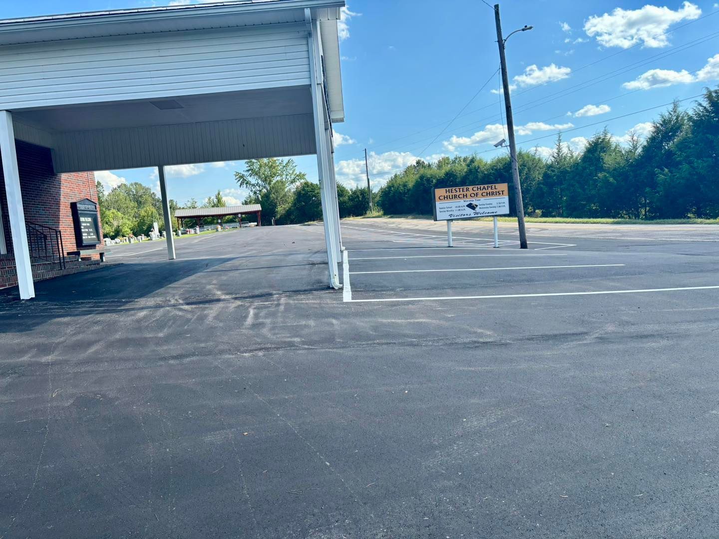 Empty parking lot beside a covered drive-through lane under a blue sky