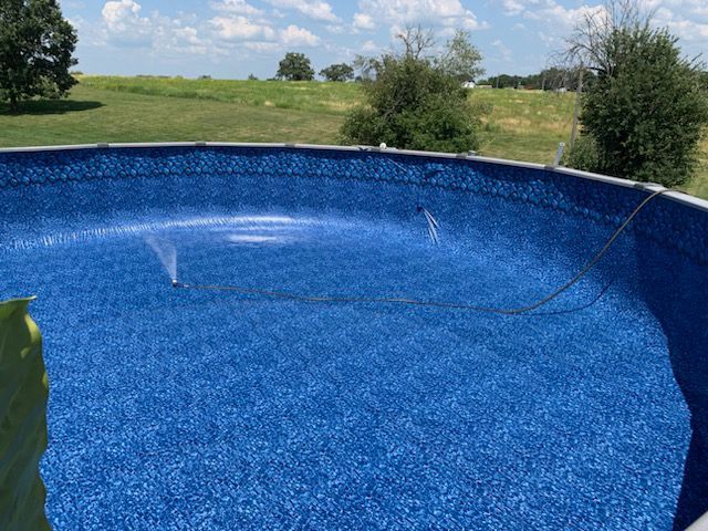 A large blue swimming pool with a sprinkler attached to it