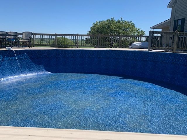 A large blue swimming pool with a deck in the background