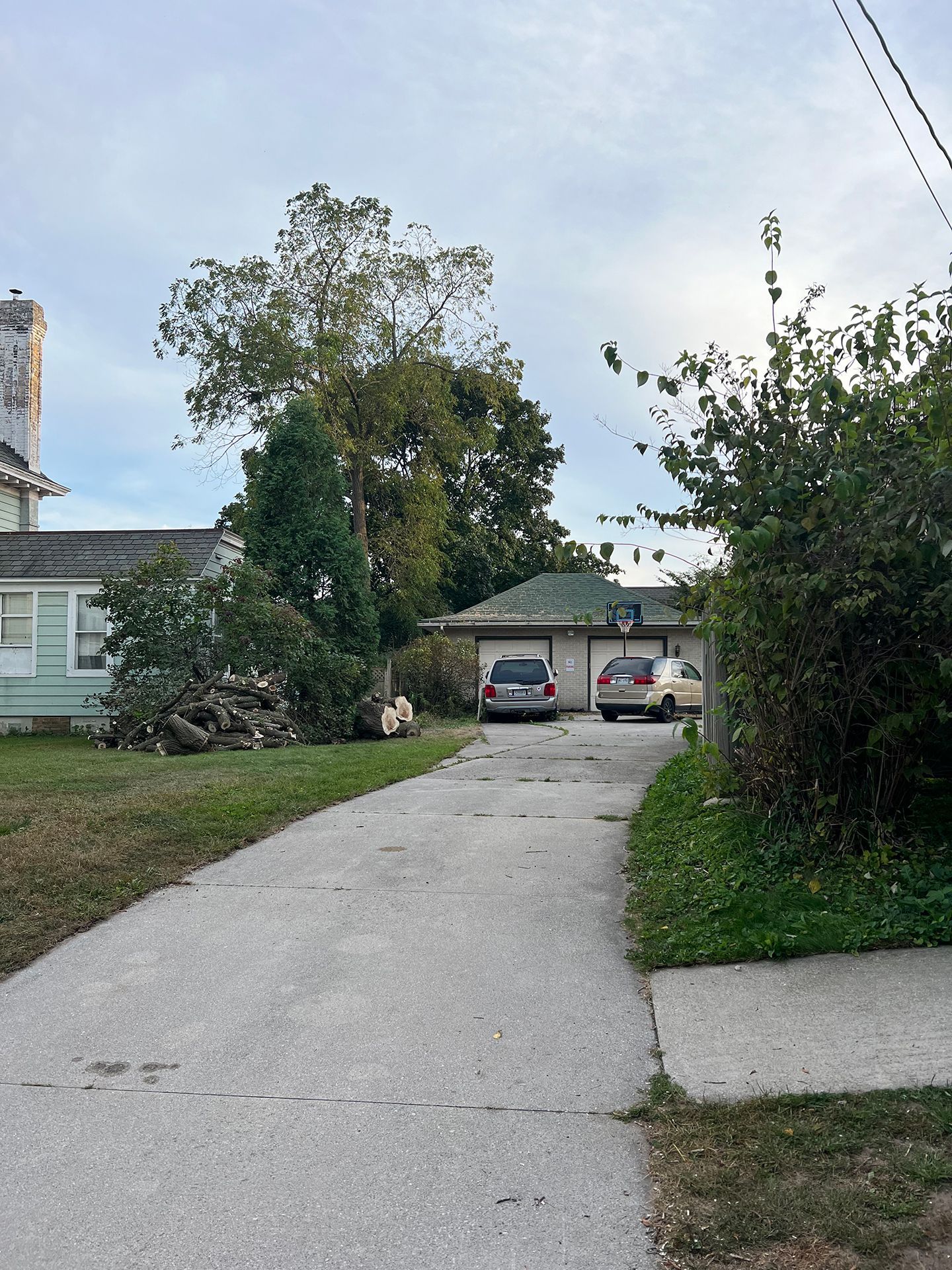 A couple of cars are parked on the side of a road in front of a house.