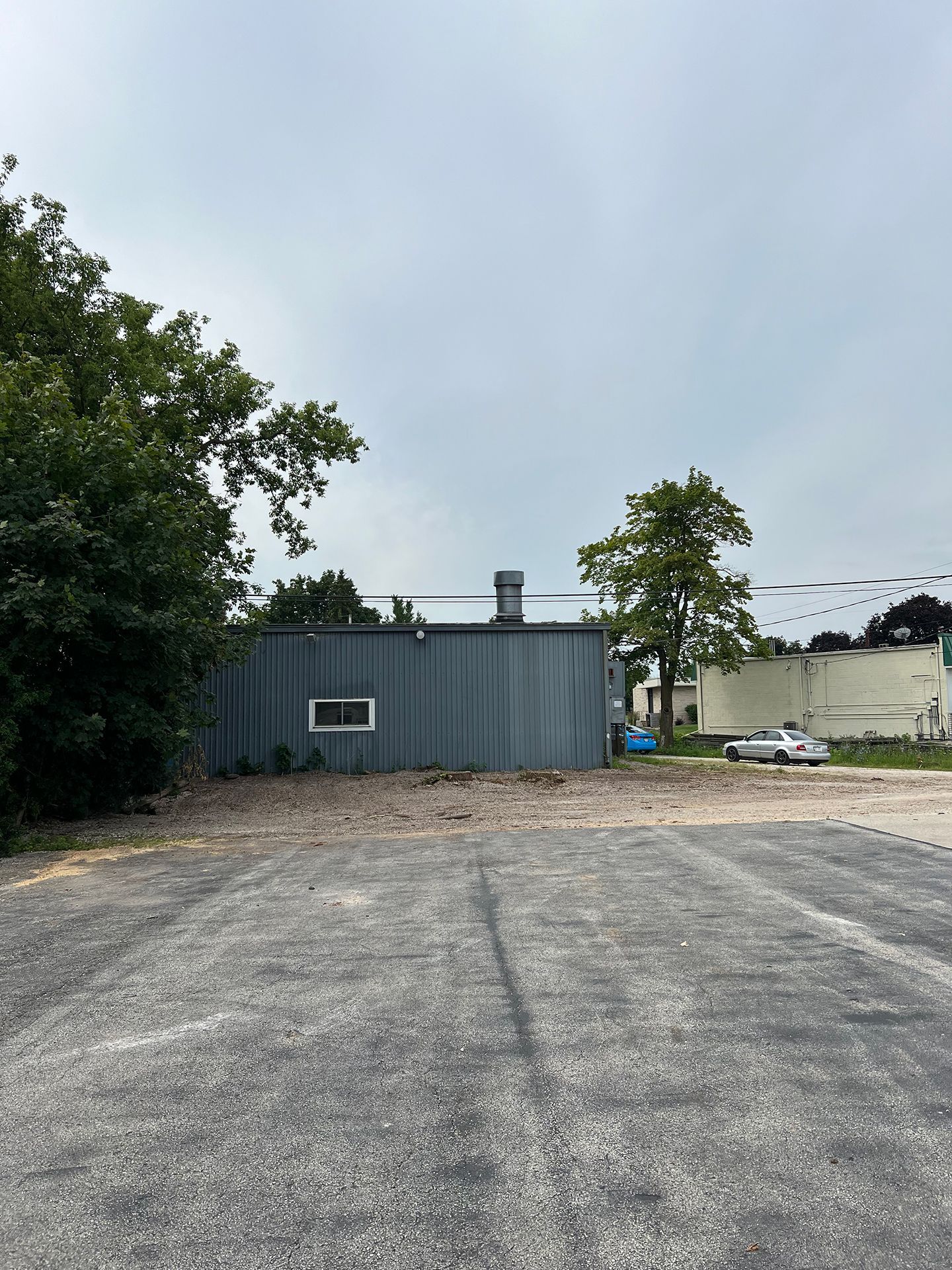 A parking lot with a building in the background and trees in the foreground.