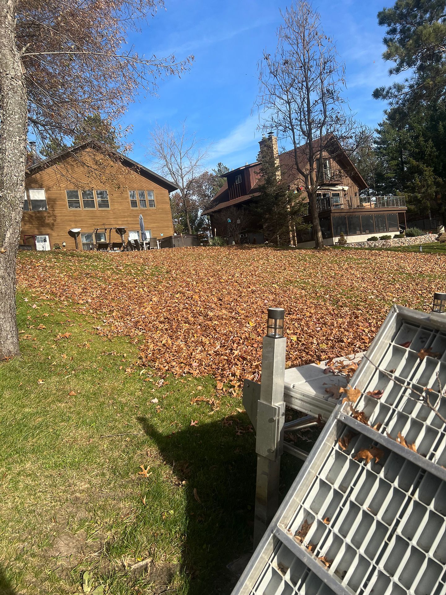 A large pile of leaves in a yard with a house in the background.