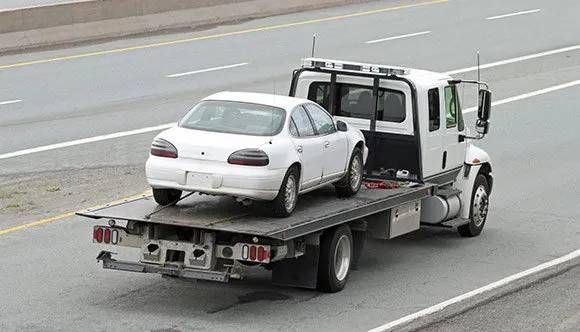 white car on flatbed tow truck