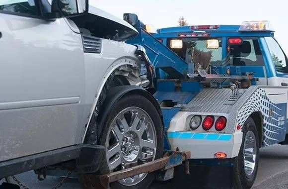 man with damaged car getting put on tow truck