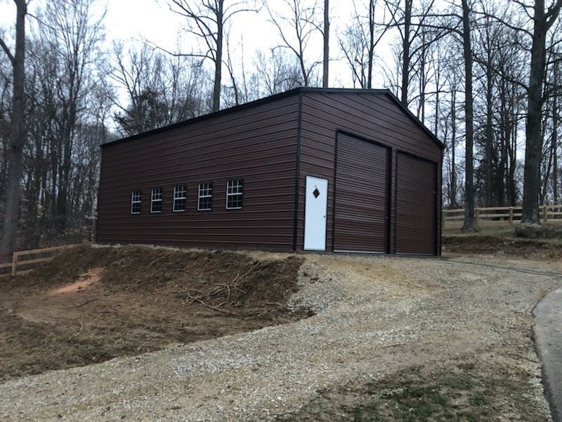 A brown metal garage with a white door and windows