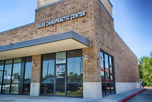 Front exterior of a brick chiropractic center with large glass windows and blue awning
