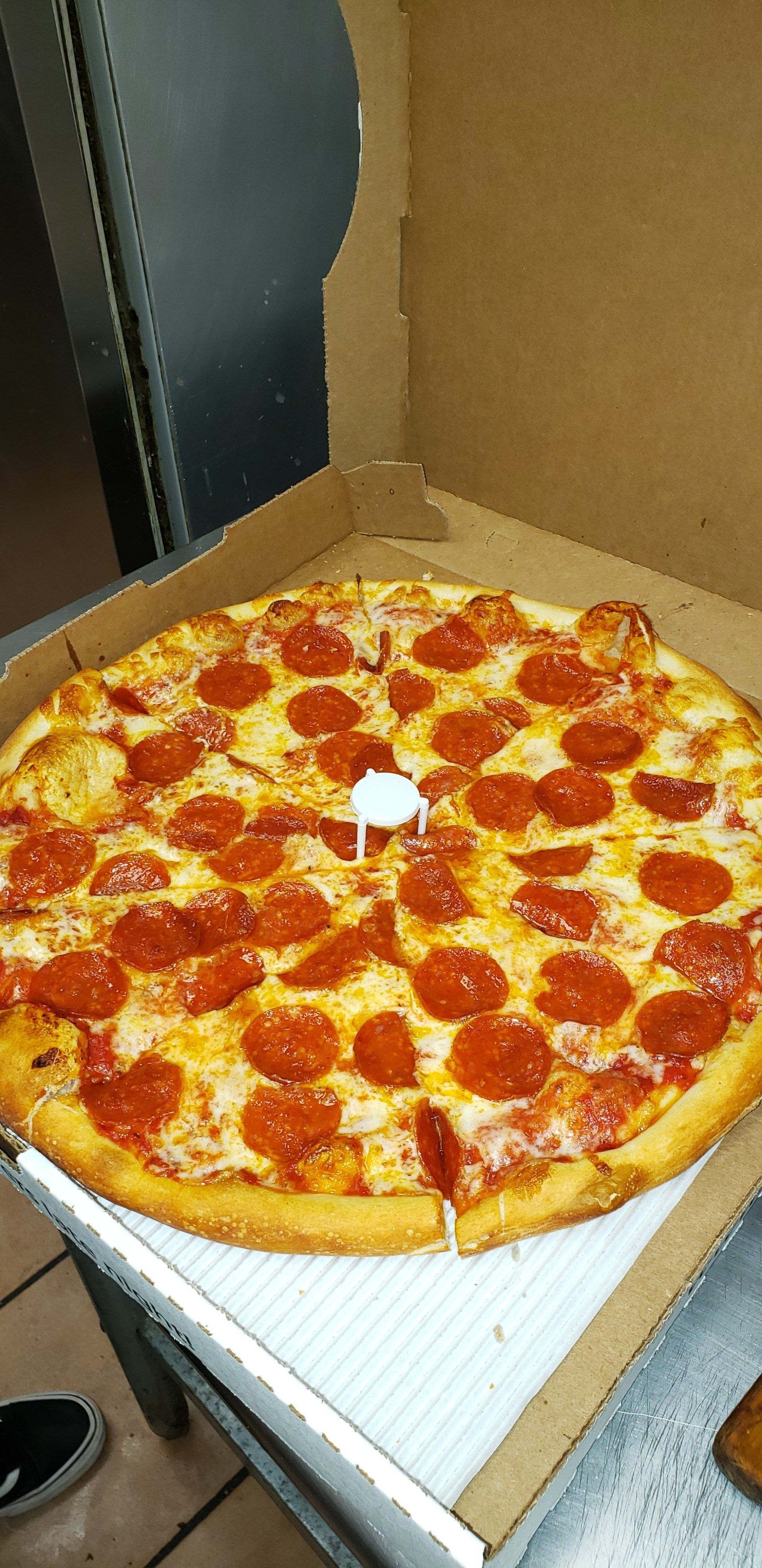 A pepperoni pizza is sitting in a cardboard box on a table.