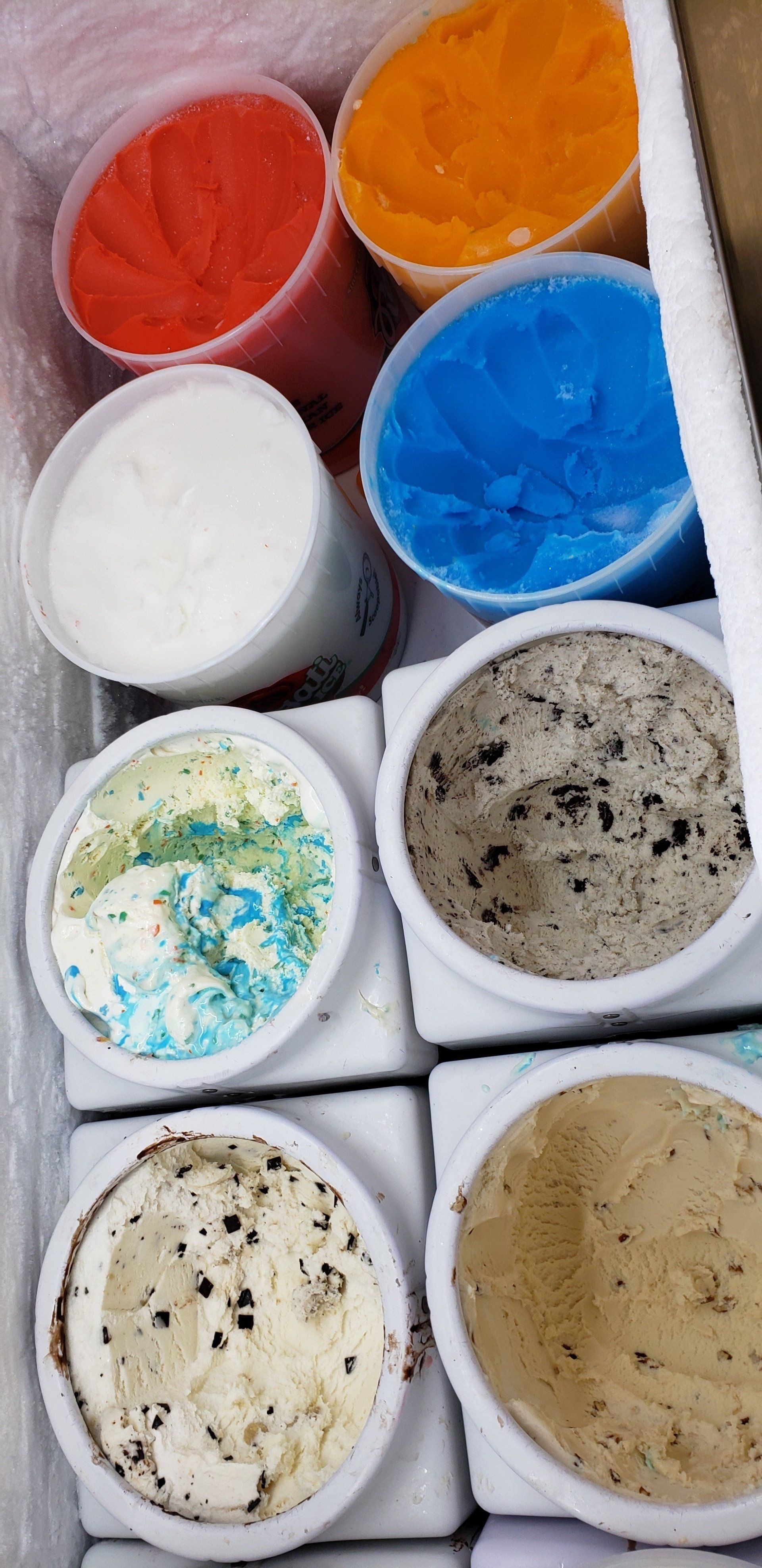 A cooler filled with ice cream cups of different flavors.