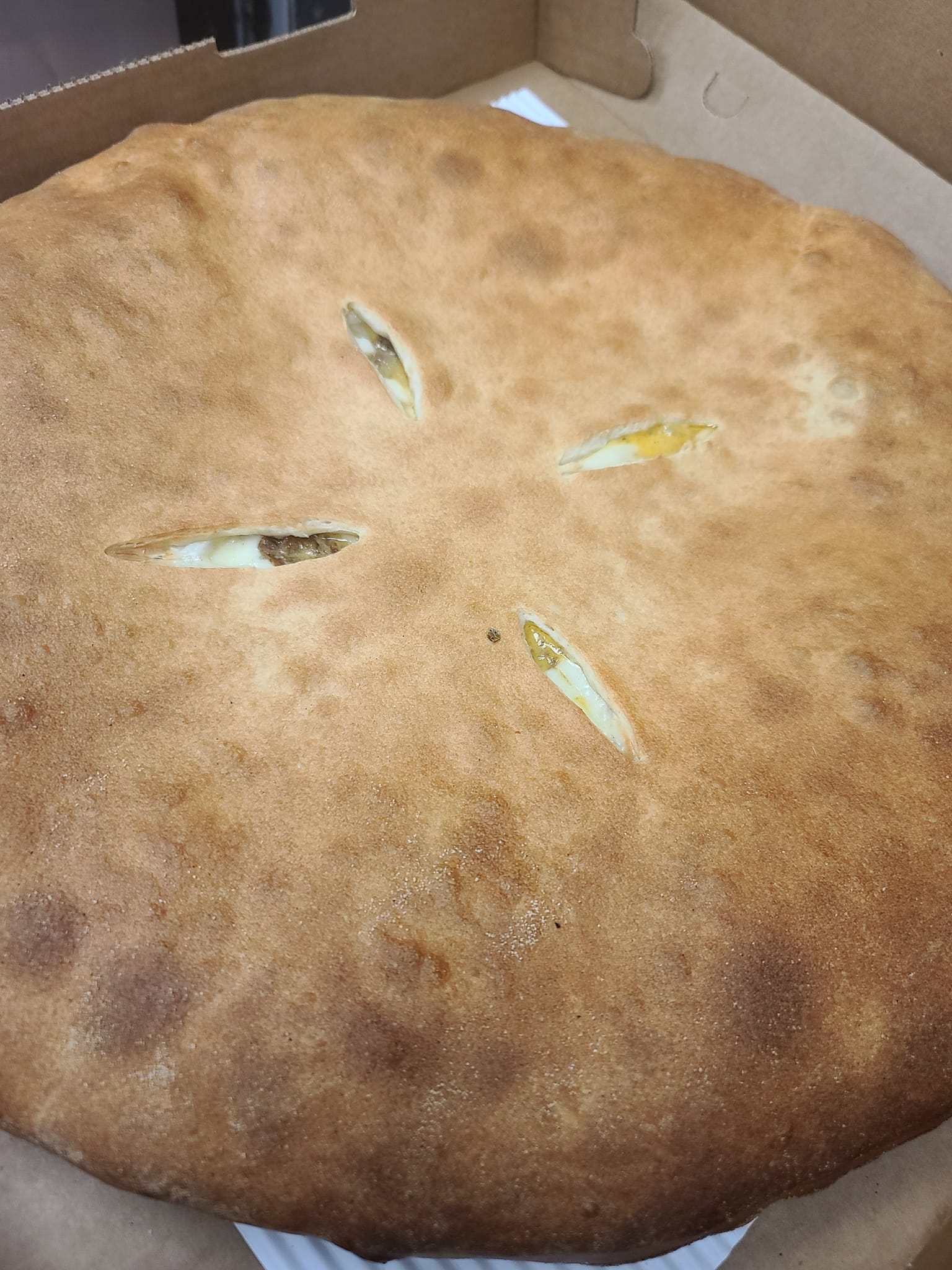 A large pizza is sitting in a cardboard box.