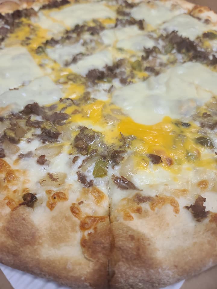 A pizza with a lot of cheese and meat on it is in a box.