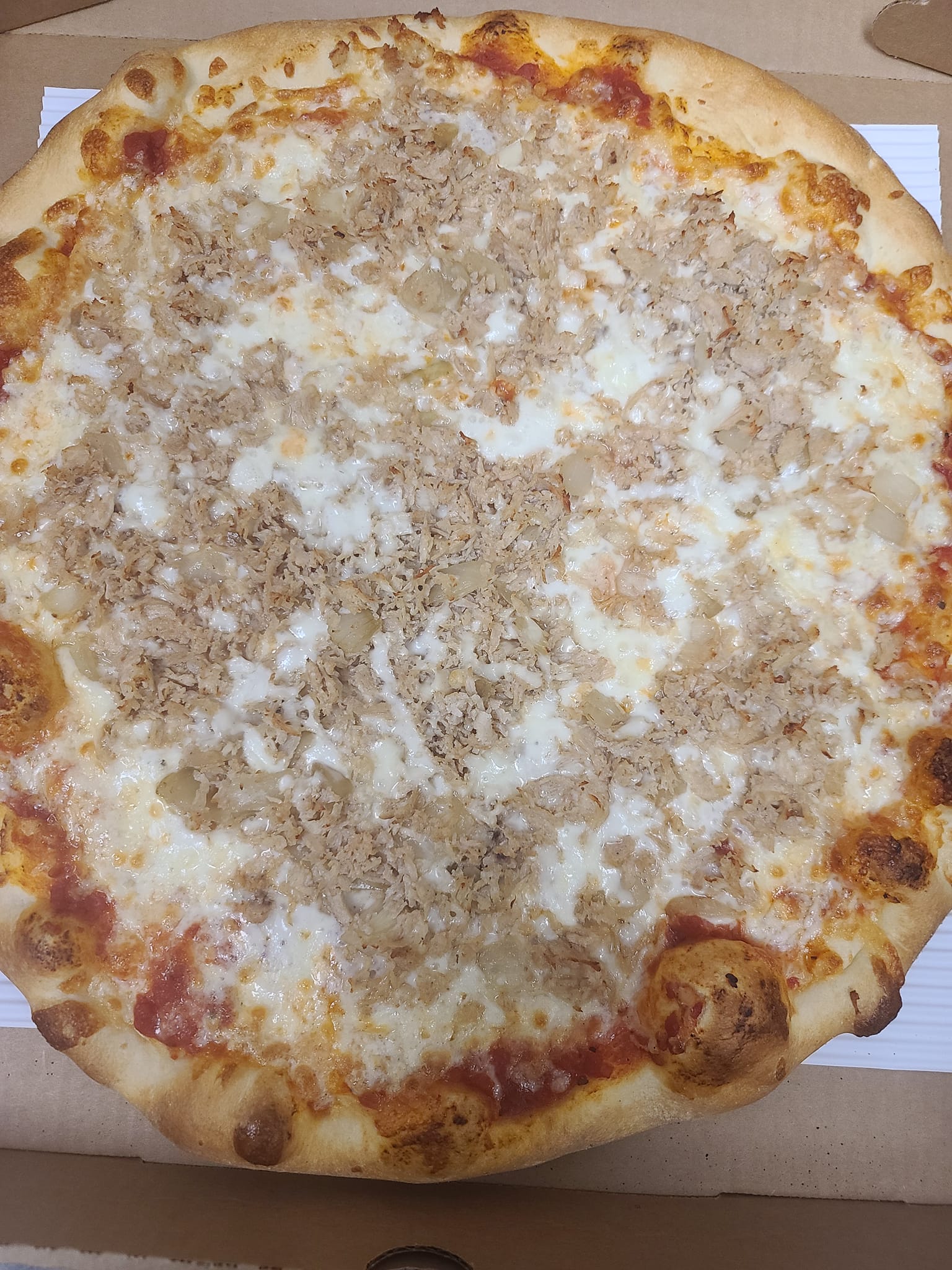 A pizza with a lot of cheese and meat on it is in a box.