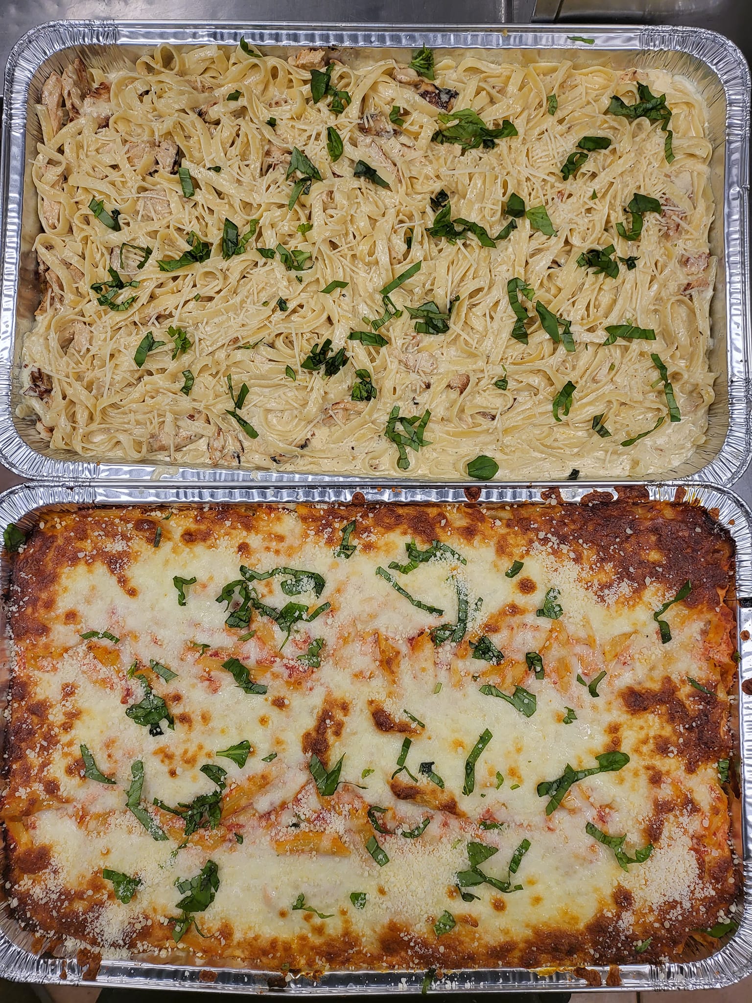 Two pans of lasagna are sitting on top of each other on a table.
