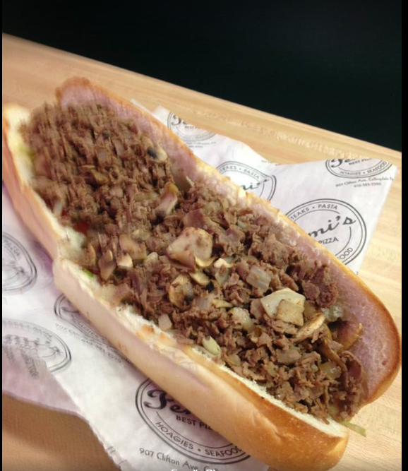 A sub sandwich is sitting on a piece of paper on a table.