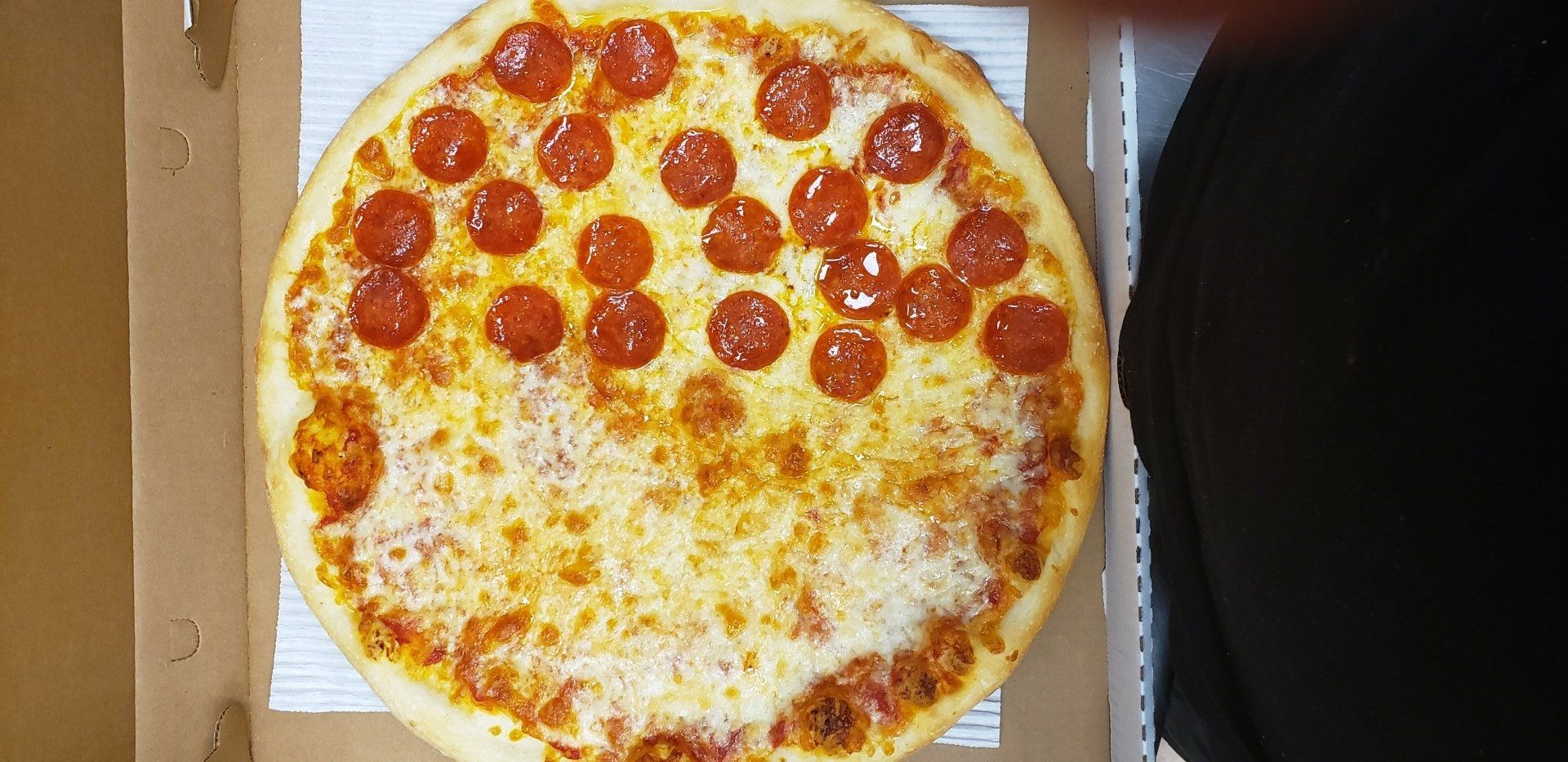 A pepperoni pizza is sitting in a cardboard box.