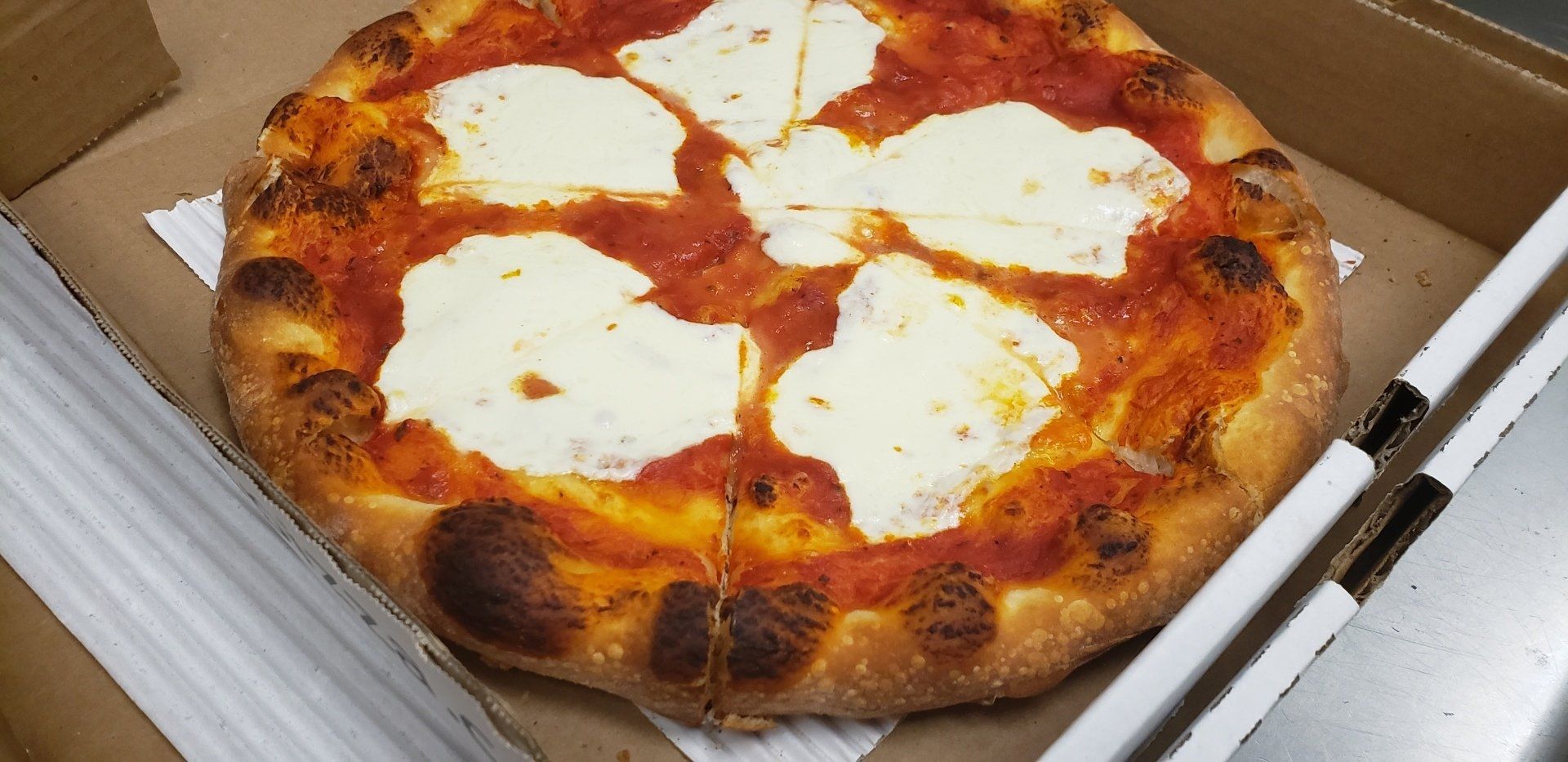 A pizza with tomato sauce and cheese is in a cardboard box.