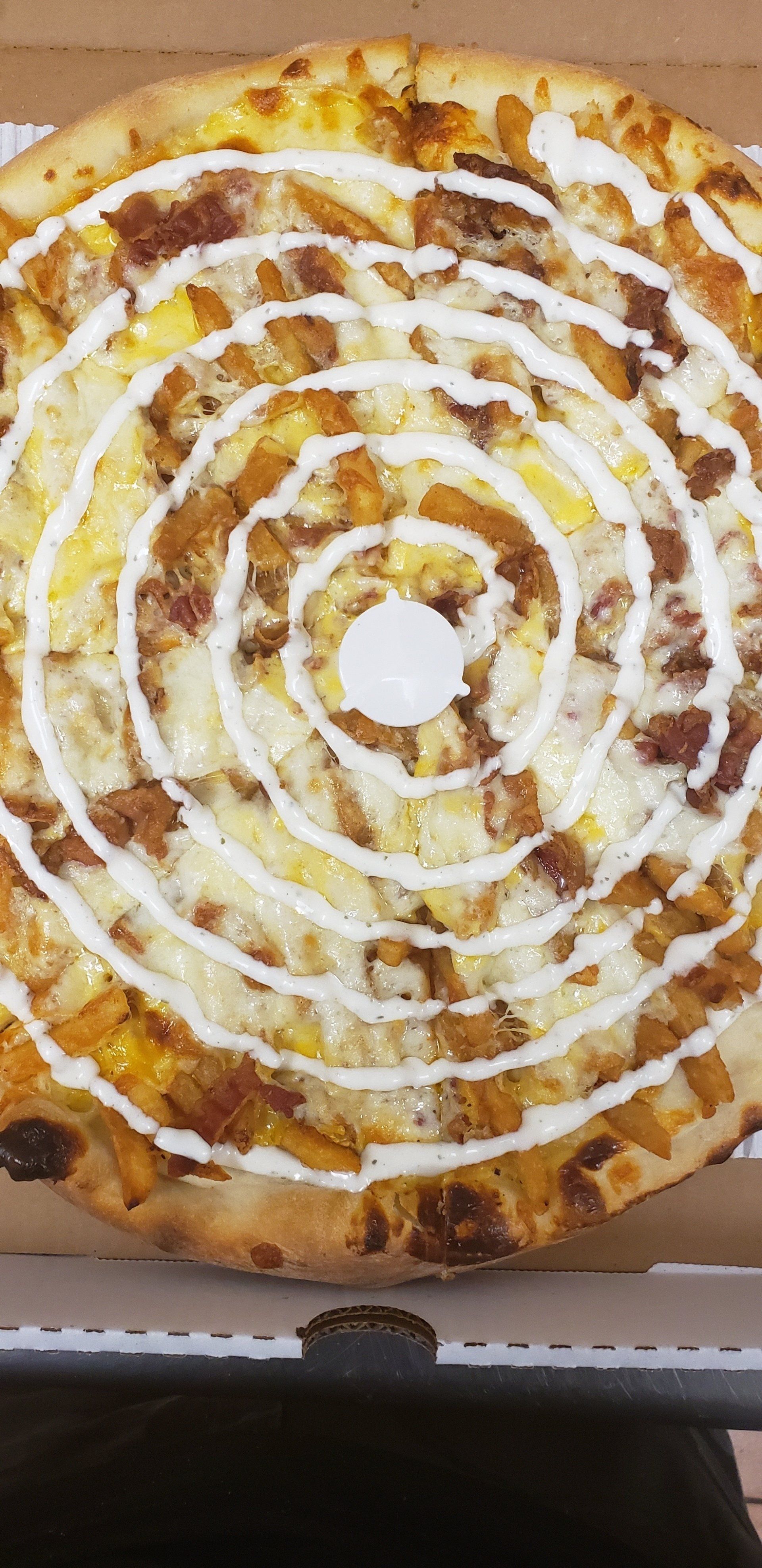 A pizza with a swirl of sauce on it is in a box.