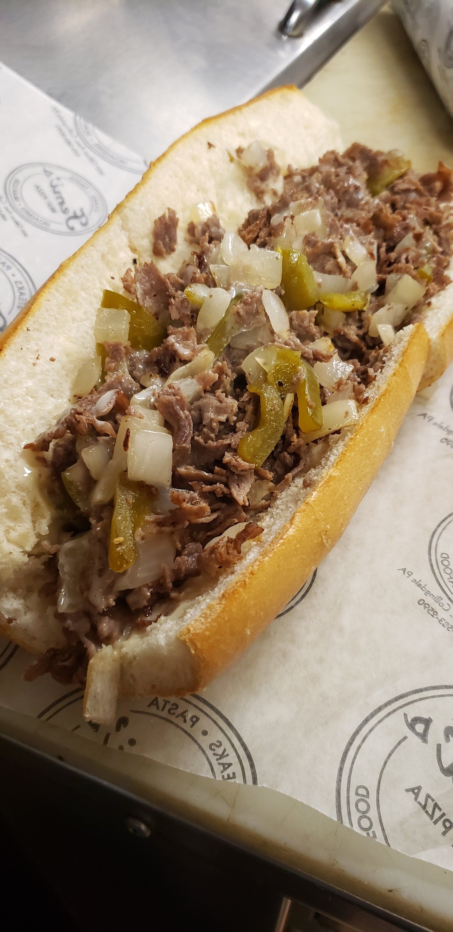 A close up of a steak sandwich on a bun on a table.