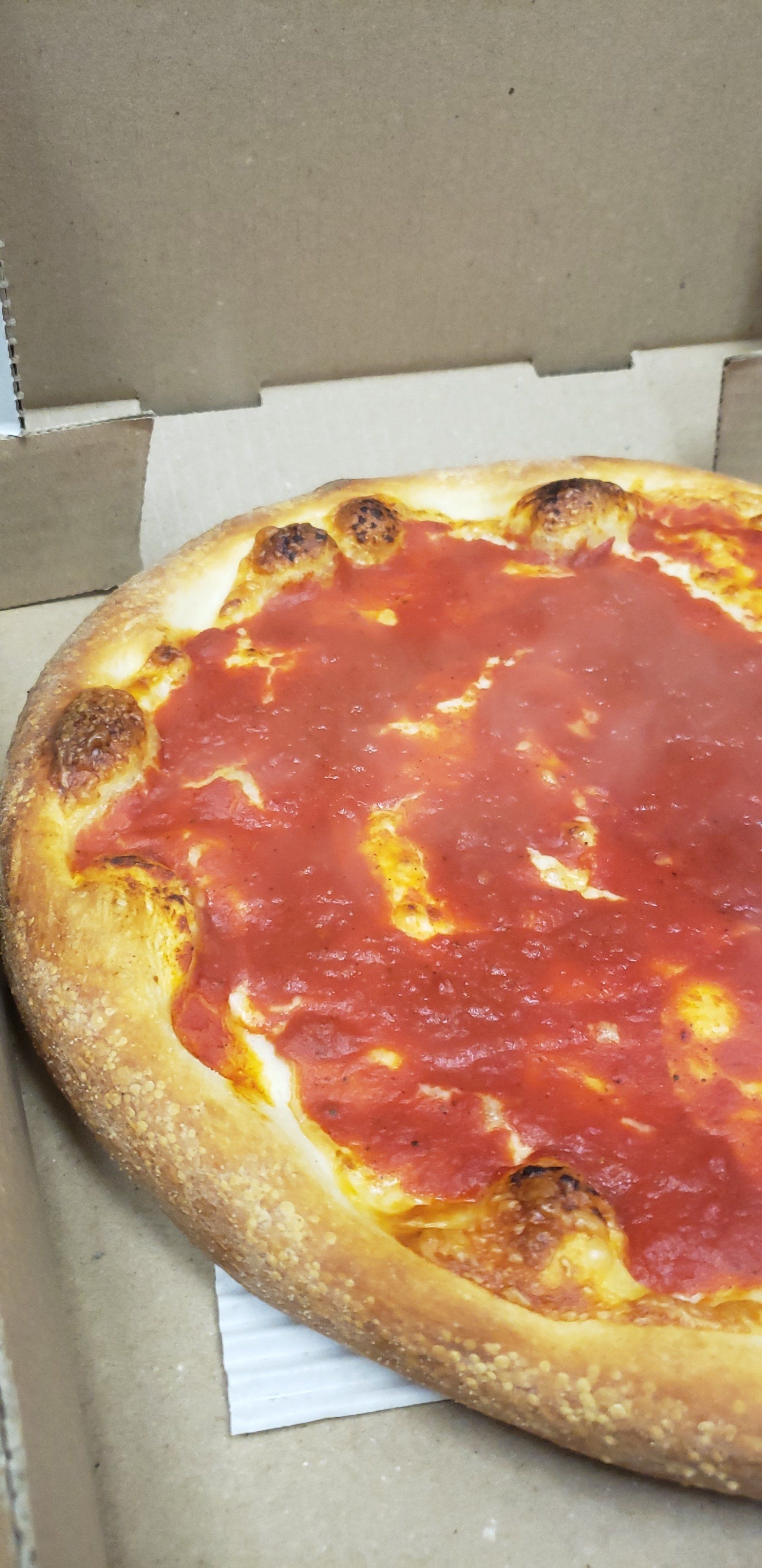 A pizza with tomato sauce on it is in a cardboard box.