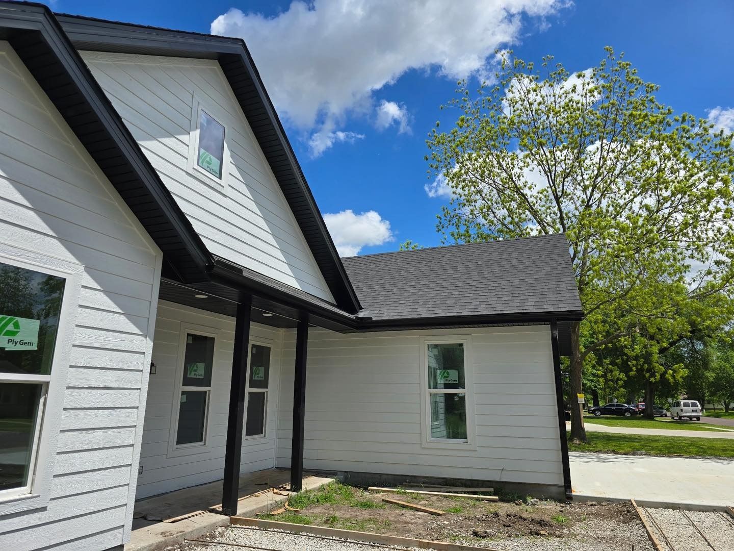 White house with dark trim and roof against a blue sky with clouds.