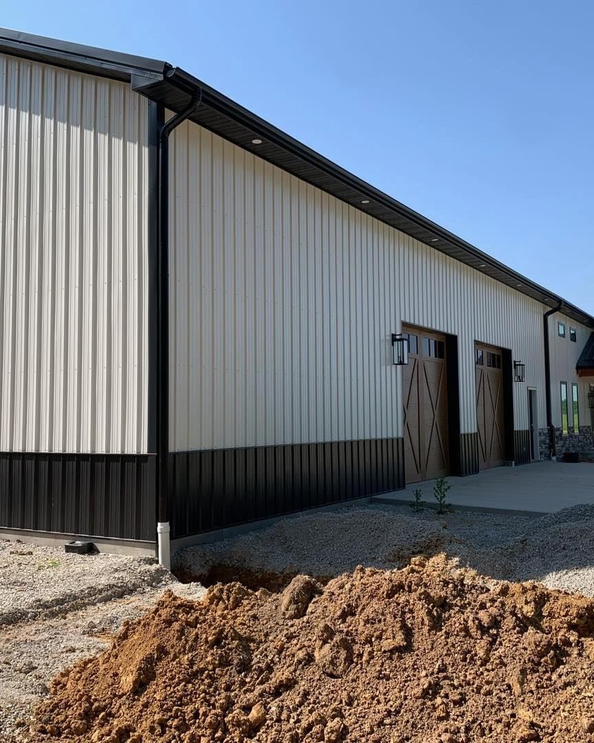 Exterior of a building with white and dark metal siding, black trim, and a concrete patio.