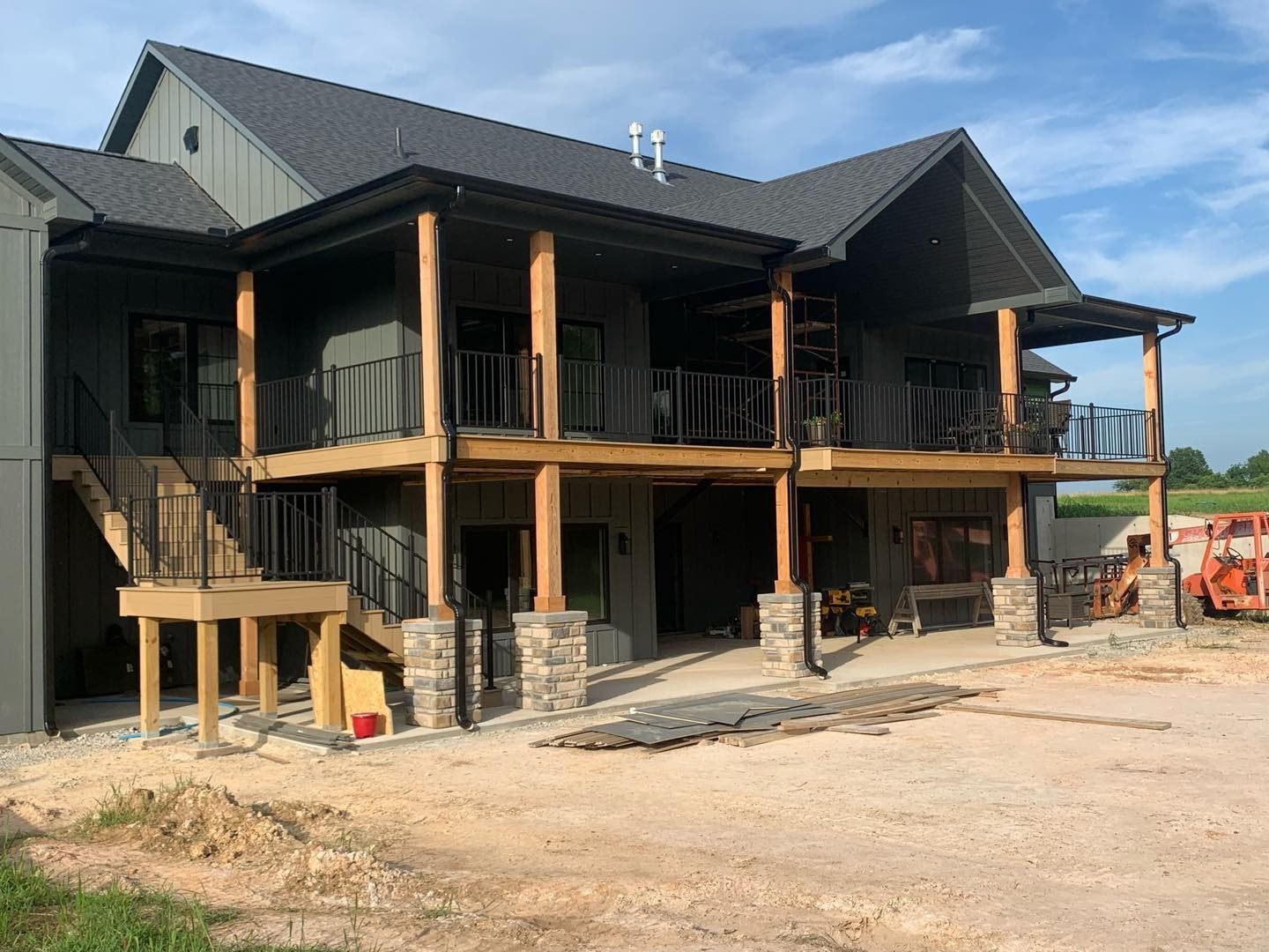 Two-story building under construction with a wraparound porch and dark gray exterior.