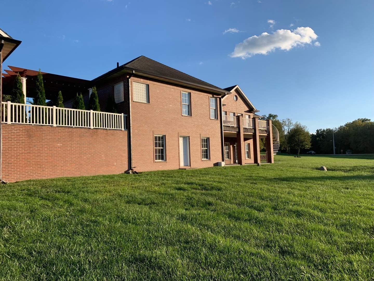 Brick house exterior with grass lawn and blue sky.