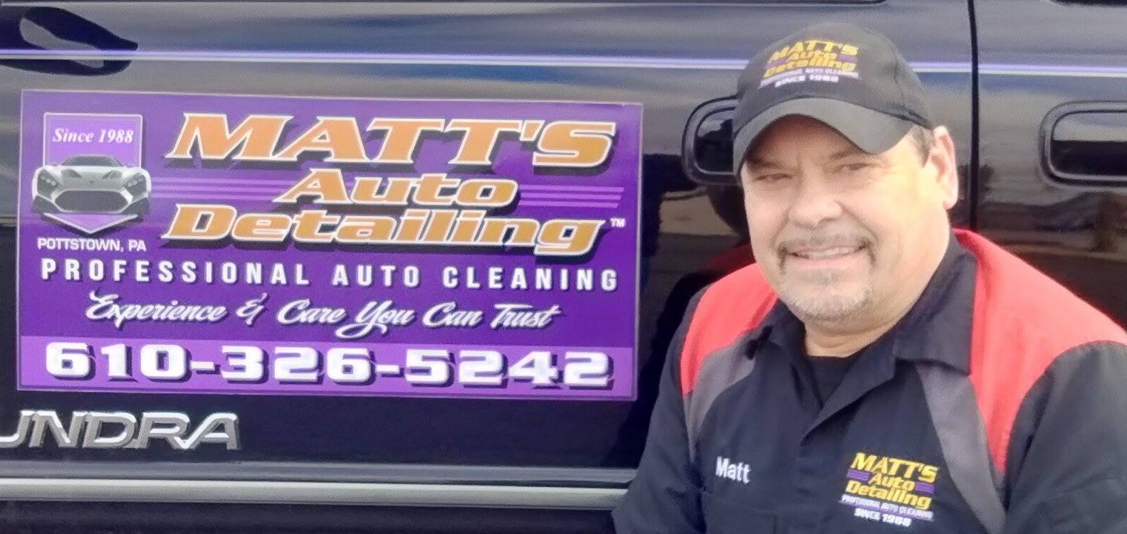 A smiling man wearing a company hat and shirt stands in front of a purple Matt's Auto Detailing truck sign.