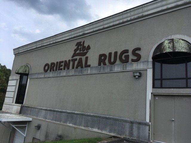 A dirty building with a sign that says oriental rugs