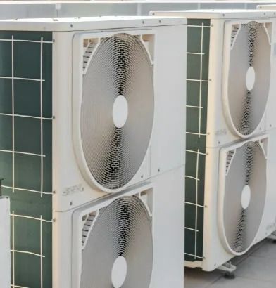 Outdoor air conditioner condenser units with large circular fans stacked side by side