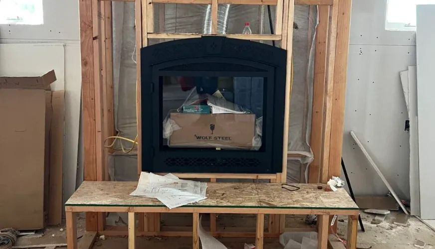 Black fireplace insert set in an unfinished wooden wall during home renovation