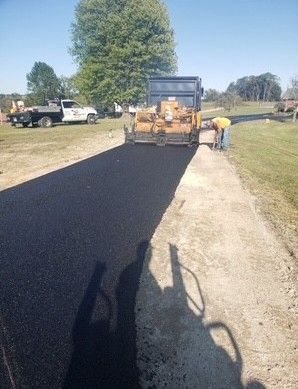 Asphalt paving of a road by a machine, worker nearby