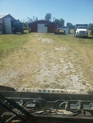 A dirt path leads to a red barn and buildings