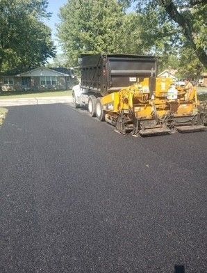 Asphalt paving machine laying fresh black pavement on a residential street