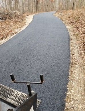 Newly paved asphalt path winding through a wooded area