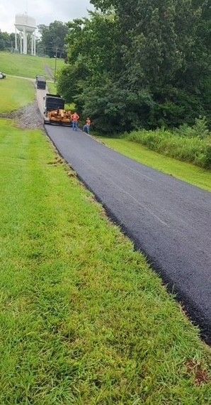 Asphalt paving a road, with workers and machinery visible