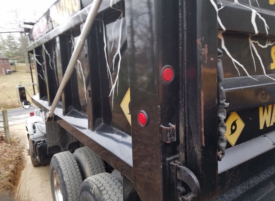 Black dump truck with yellow and white lightning bolt designs; red lights