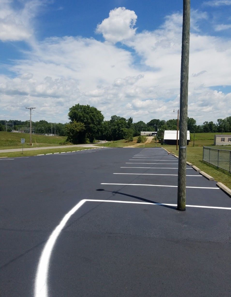 Newly paved asphalt parking lot with white painted lines and utility pole