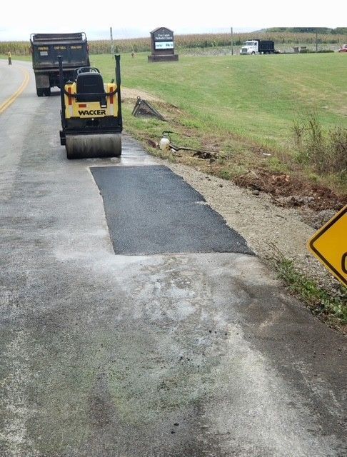 Road repair in progress: Roller compacting fresh asphalt patch