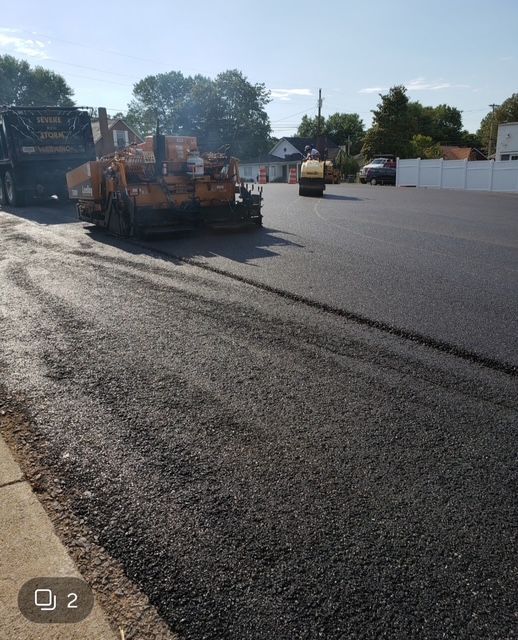Asphalt paving in progress: truck, paving machine, roller