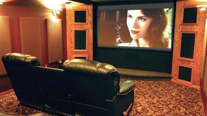 A home theater with a large screen and a woman on it