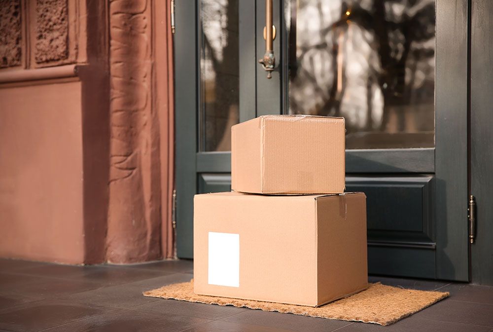 Two cardboard boxes are stacked on top of each other on a door mat.